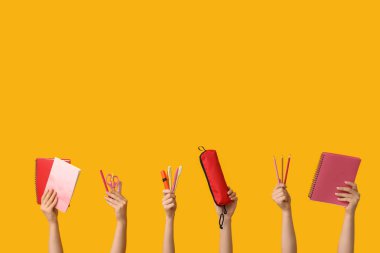 Sarı arka planda farklı kırtasiye malzemesi olan kadın elleri