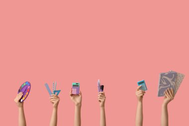 Pembe arka planda farklı kırtasiye malzemesi olan kadın elleri