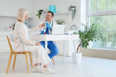 Klinikteki kadın hastaya reçete yazan erkek endokrinolojist.