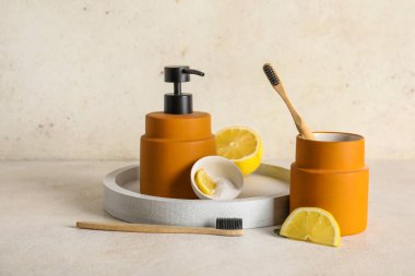 Bir kase limonlu diş pudrası, fırça, tutucu ve sabun makinesi beyaz arka planda.
