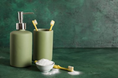 Bir kase diş pudrası, fırça, tutucu ve sabun makinesi yeşil grunge arka planda.