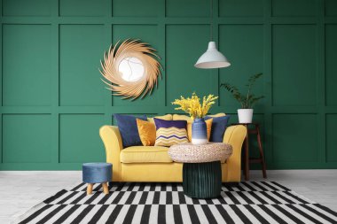 Sarı kanepeli, puflu ve aynalı şık bir oturma odası.