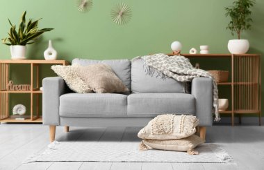 Şık oturma odasında yumuşak yastıklı gri kanepe.