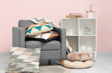 Yumuşak yastıklı gri koltuk ve şık oturma odasında battaniye.