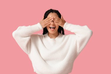 Pembe arka planda güzel, mutlu, Afro-Amerikan bir kadın.