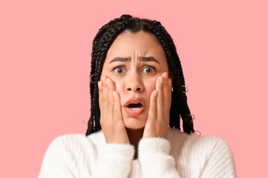 Pembe arka planda güzel, korkmuş, Afro-Amerikalı bir kadın.