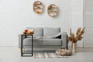 Evdeki masada balkabağı, kitap ve çay fincanı şeklinde yanan mumlarla dolu hasır sepet.