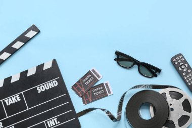 Sinema biletleri, uzaktan kumanda ve mavi arka planda film makaraları olan alkışlar.