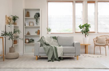 Oturma odasının içinde ekoseli, raflı ve çiçekli rahat bir kanepe.