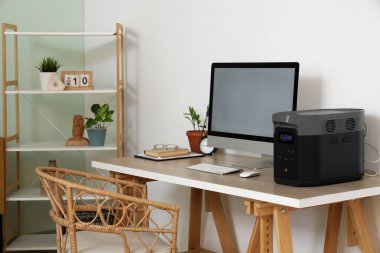 Odada bilgisayar ve taşınabilir elektrik santrali olan modern işyeri