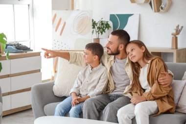 Babaları evdeki kanepede oturan sevimli küçük çocuklar.
