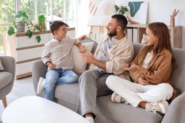 Babaları evdeki kanepede oturan sevimli küçük çocuklar.