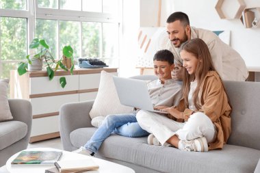 Babaları evde dizüstü bilgisayar kullanan sevimli çocuklar.