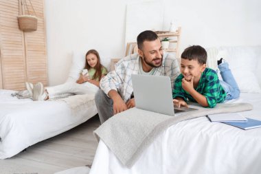 Babalarıyla birlikte yatak odasında vakit geçiren sevimli küçük çocuklar.