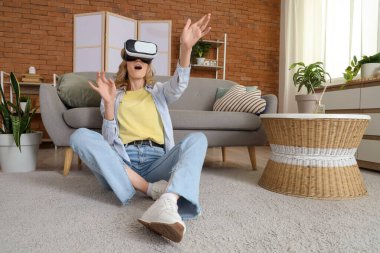 Evde VR gözlük takan güzel bir genç kadın.