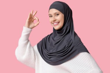 Genç Müslüman kadın pembe arka planda iyi görünüyor.