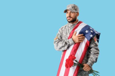 Amerikan bayrağı taşıyan erkek asker ve karanfil çiçekleri mavi arka planda dua ediyor. Gaziler Günü kutlamaları