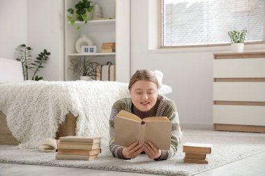 Güzel, genç, mutlu bir kadın evde kitap okuyor.