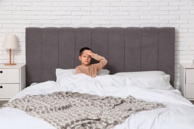 Yatak odasında boğazı ağrıyan küçük Asyalı çocuk.