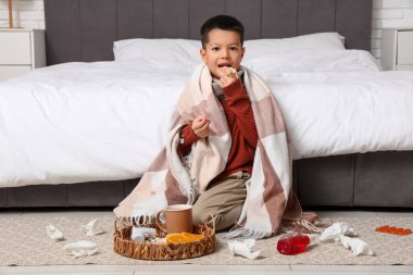 Boğazı ağrıyan, yatak odasında limon yiyen küçük Asyalı çocuk.