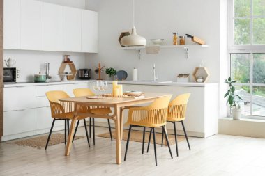 Mutfakta gözlük, sofra takımı ve mumlarla dolu yemek masası.