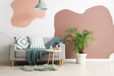 Oturma odasının iç tarafında rahat bir kanepe, çiçek ve kahve masası.