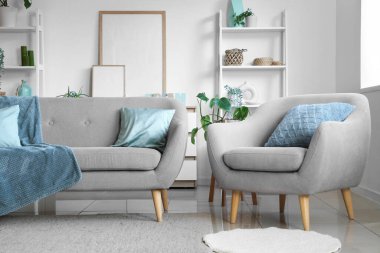 Oturma odasının iç tarafında rahat bir kanepe, koltuk ve çiçek var.