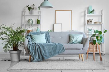 Oturma odasının iç tarafında rahat bir kanepe ve çiçek var.