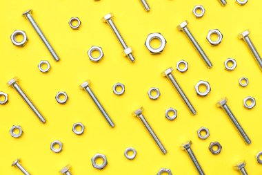 Sarı arka planda bir sürü cıvata ve krom fındık