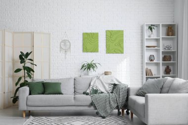 Oturma odasının içinde rahat koltuklar ve resimler var.