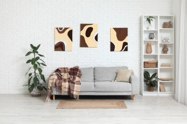 Oturma odasının içinde yastıklı, ekoseli ve resimli rahat bir kanepe.