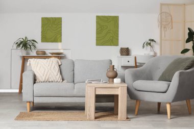 Konforlu kanepe, koltuk, kahve masası ve oturma odasının içindeki resimler.