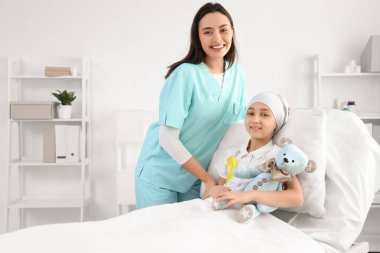 Kemoterapiden sonra sarı kurdeleli ve klinikte hemşirelik yapan küçük bir kız. Çocukluk kanseri farkındalığı
