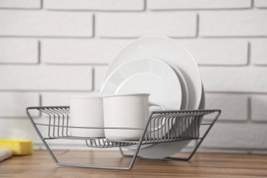 Ahşap mutfak tezgahında temiz tabaklar ve fincanlar olan metal askı.