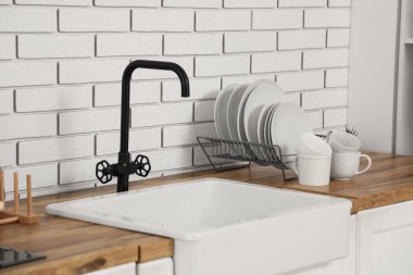 Lavabonun yanındaki tahta masada temiz tabaklar ve bardaklarla diz.