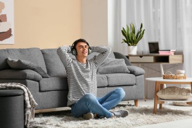 Evde müzik dinleyen kulaklıklı yakışıklı bir genç.