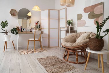 Makyaj masası, katlanır ekran ve koltuk olan hafif soyunma odasının içi.