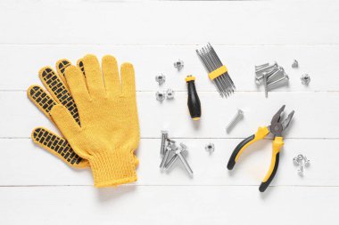 Beyaz ahşap arka planda musluk cıvataları, eldivenler ve aletler