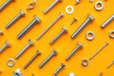 Turuncu arka planda farklı musluk cıvataları, vidalar ve krom fındıklar düzenleme