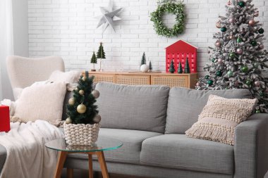 Oturma odasının içinde Noel ağaçları ve kanepe var.