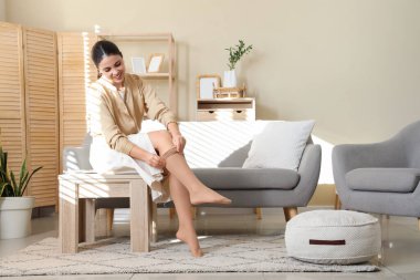 Genç kadın kanepede otururken tayt giyiyor.