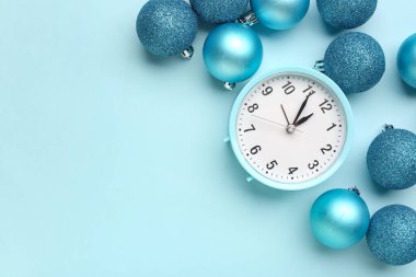 Composition with alarm clock and beautiful Christmas balls on color background clipart