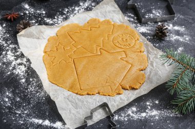 Ham hamur ve kesiciler karanlık arka planda Noel kurabiyeleri hazırlamak için