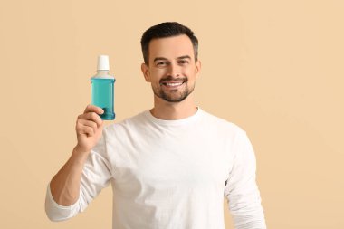 Ağzı bej arkaplanda durulanmış yakışıklı adam.