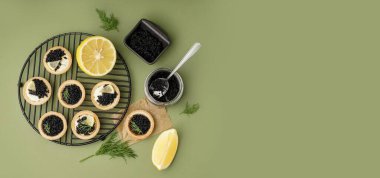 Yeşil arkaplanda siyah havyarlı lezzetli tartlar ve metin için yer var.