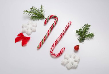 Şeker kamışları, köknar dalları ve beyaz arka planda Noel süslemeleri