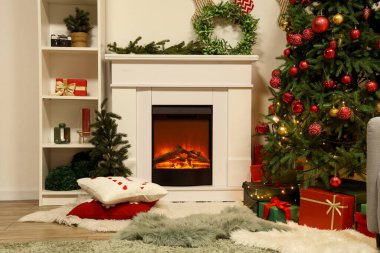 İçinde şömine, ökse otu çelengi ve süslü Noel ağacı olan festival salonu.