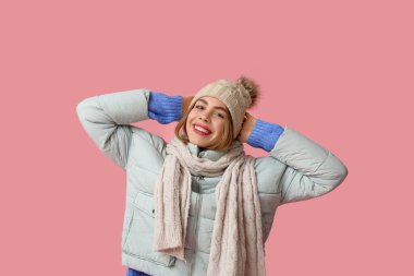 Pembe arka planda kışlık giysiler içinde güzel, mutlu bir kadın.