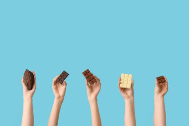 Farklı çikolata ve mavi arka planda kakao kabuğu olan kadın elleri.