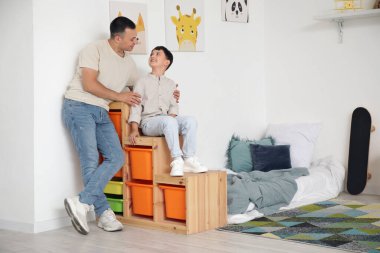 Babası yatak odasında olan sevimli küçük bir çocuk.